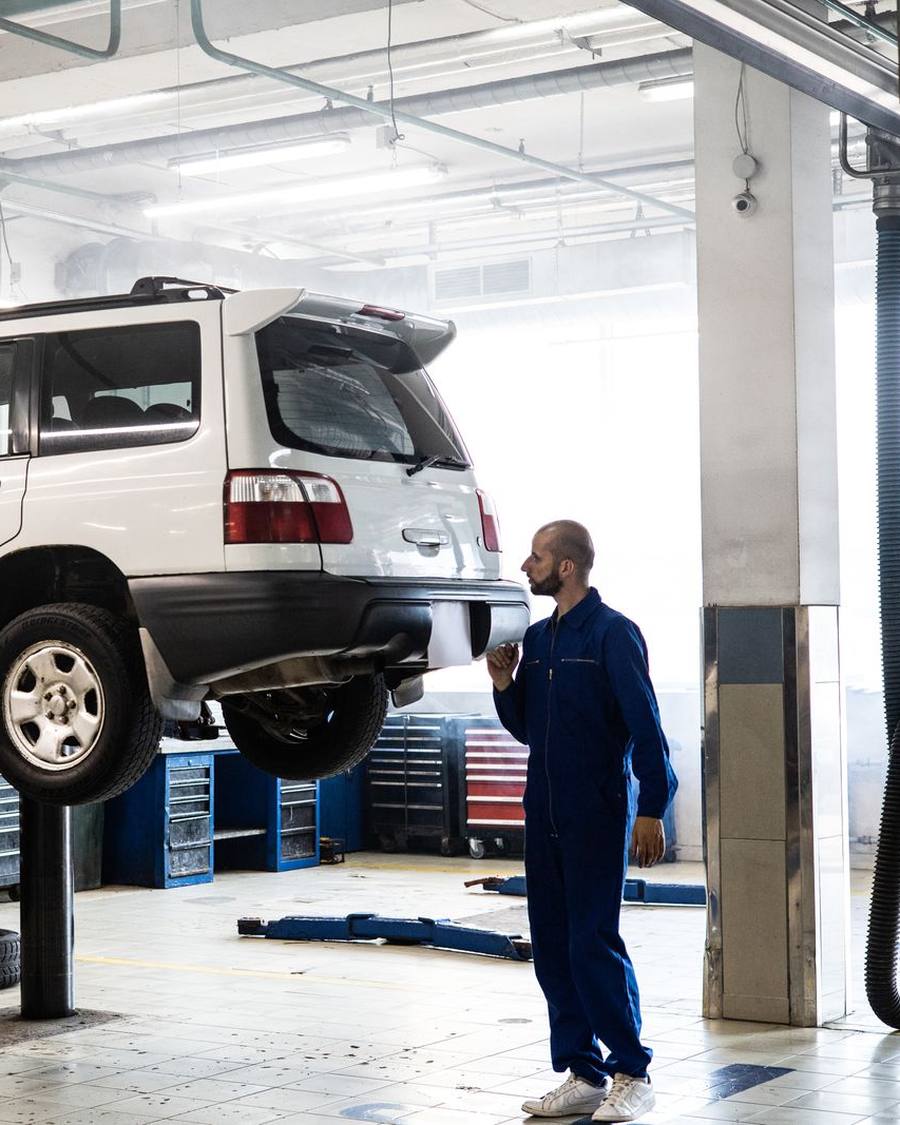 A technician inspecting a vehicle raised on a workshop lift